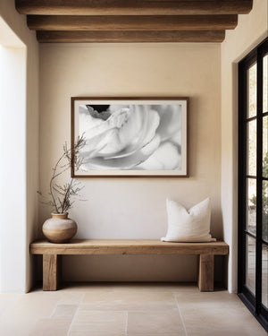 Nestled corner with a wooden bench, decorative vase, and framed black and white botanical artwork on a beige stucco wall.
